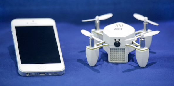 a white drone next to a cell phone