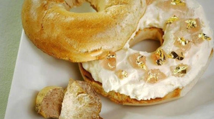 a bagel with cream cheese and gold flakes