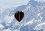 a hot air balloon in the air over snowy mountains