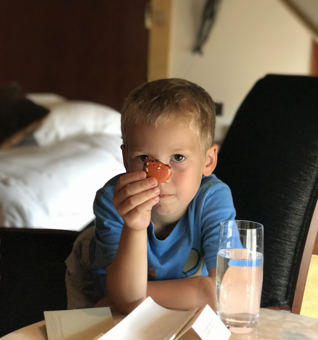 a boy holding a cookie over his eye