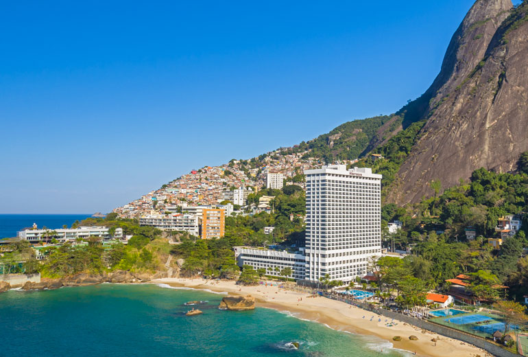 a beach with buildings and a hill