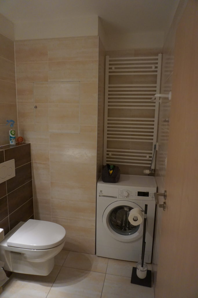 a bathroom with a washing machine and toilet