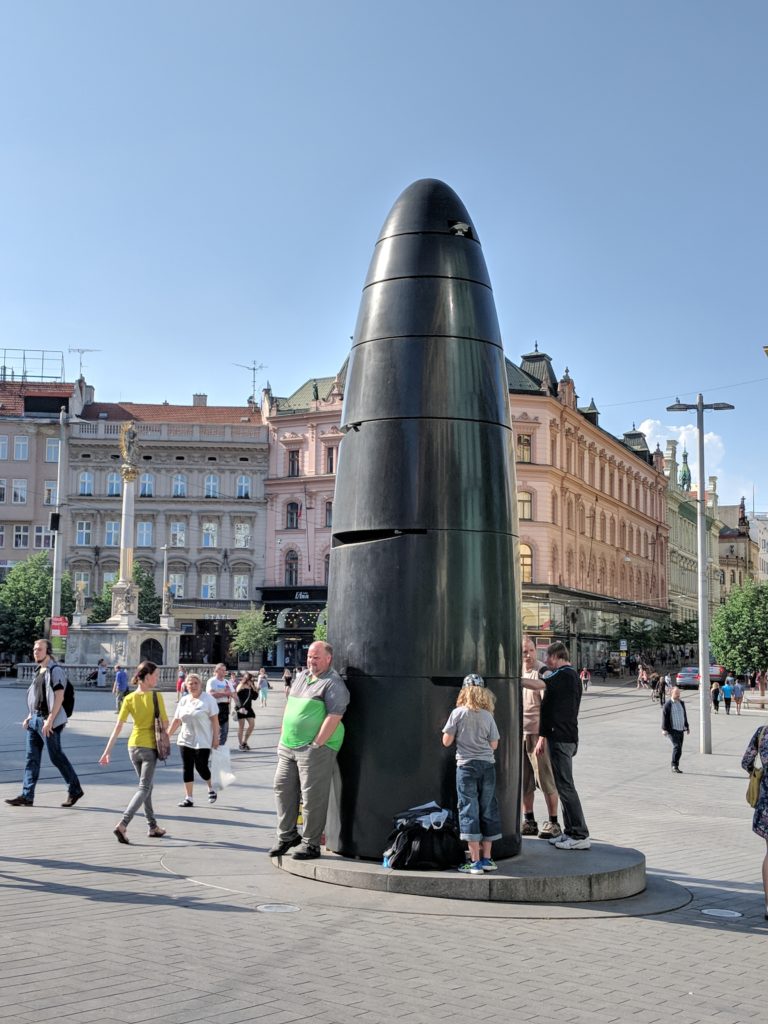 a group of people standing around a black object in a city