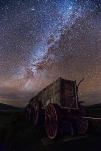 a wooden wagon with wheels and stars in the sky