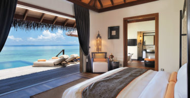 a room with a bed and a view of the ocean