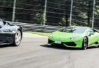 a green sports car and a black car on a road