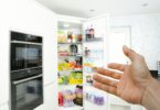 a hand reaching out to open a refrigerator