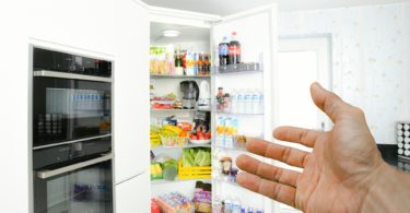 a hand reaching out to open a refrigerator