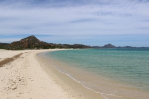 a beach with a body of water and mountains in the background