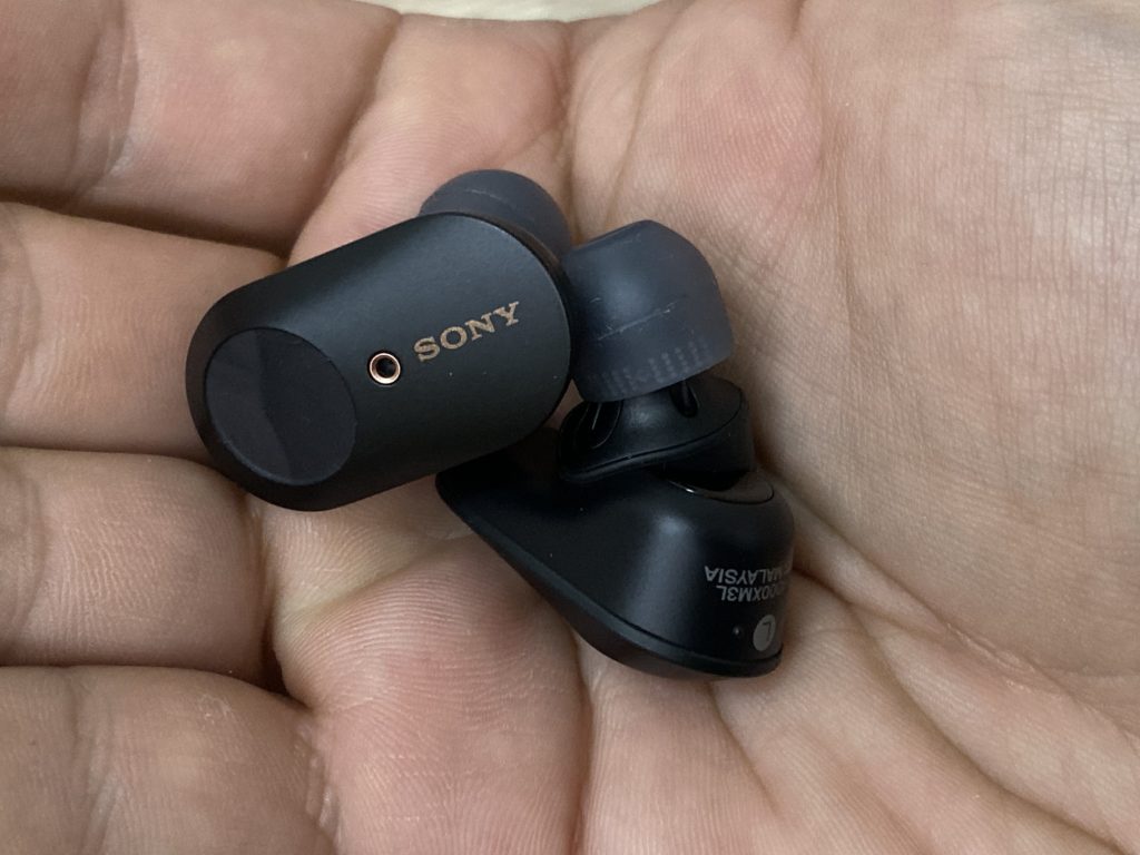 a hand holding a pair of black earbuds