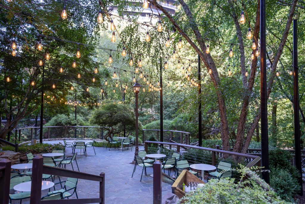 a patio with tables and chairs and lights from trees