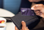 a person holding a credit card over a wallet