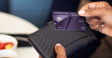 a person holding a credit card over a wallet