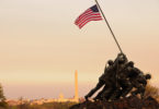 a statue of soldiers holding a flag with Marine Corps War Memorial in the background