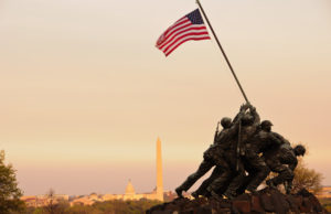 a statue of soldiers holding a flag with Marine Corps War Memorial in the background