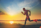 a man running on a road with a sunset in the background