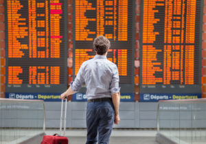 a man with a suitcase looking at a board