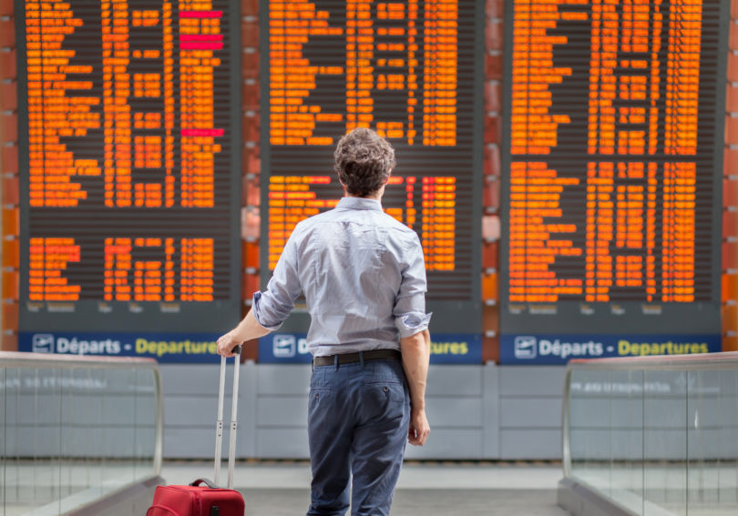 a man with a suitcase looking at a board