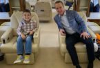 a man and boy sitting in chairs in an airplane