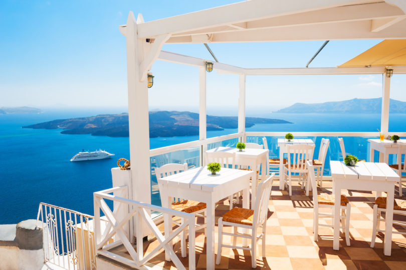a white table and chairs on a deck overlooking the ocean
