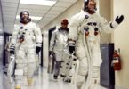 a group of people in space suits walking in a hallway
