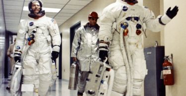 a group of people in space suits walking in a hallway
