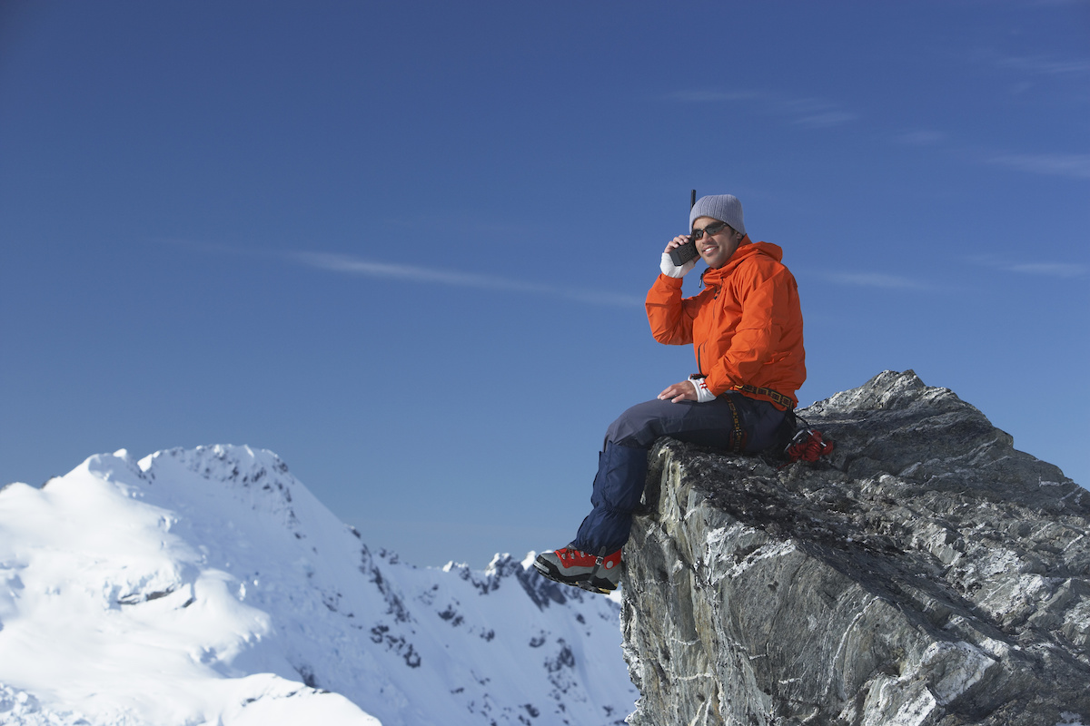 a man sitting on a rock with snow covered mountains in the background