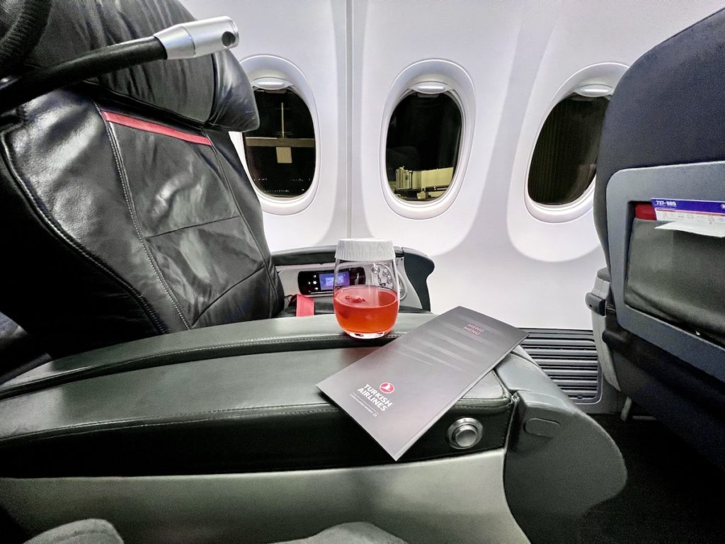 a glass of liquid on the arm of a chair in an airplane