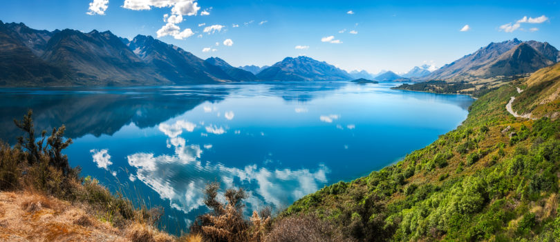 a body of water with mountains and blue sky