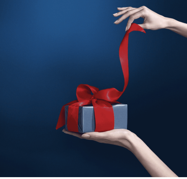 a hand holding a gift box with a red ribbon