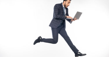 a man in a suit running with a laptop