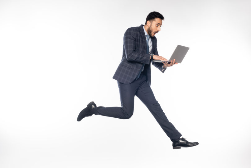 a man in a suit running with a laptop