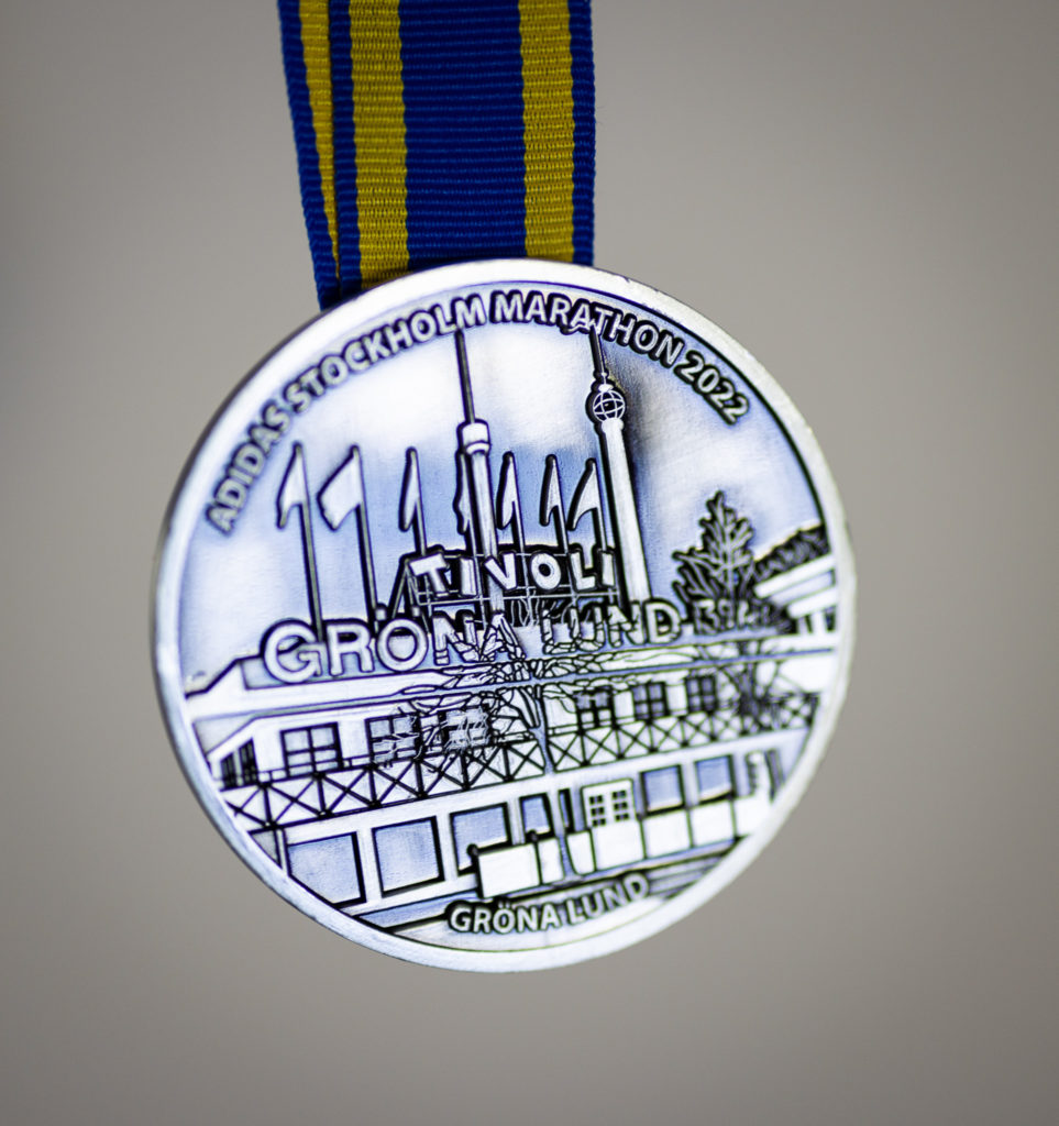 a silver medal with a blue and yellow ribbon