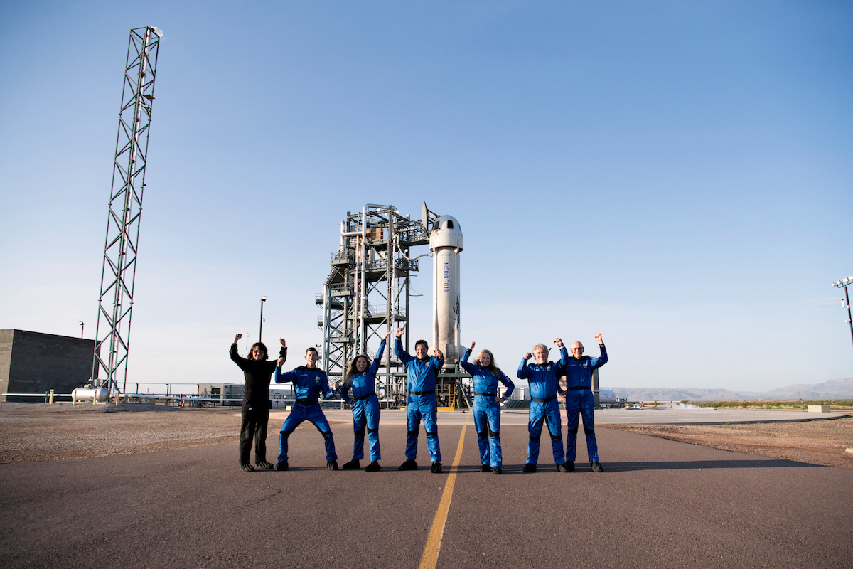 a group of people in blue overalls standing in front of a tower