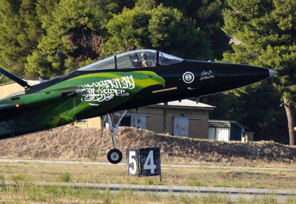 a green and black jet plane taking off