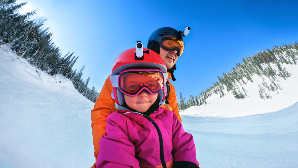 a man and child wearing ski goggles and helmets on snow