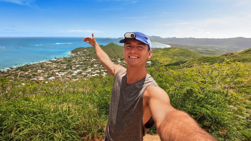 a man taking a selfie with a city and mountains in the background