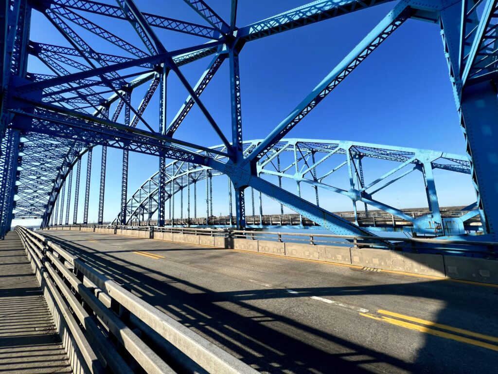 a blue metal bridge over a road
