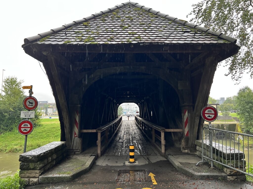 a covered bridge with a road sign and a road sign