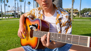 a man sitting on grass playing guitar