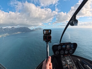 a hand holding a camera in a helicopter