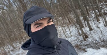 a man wearing a mask and hat in the snow