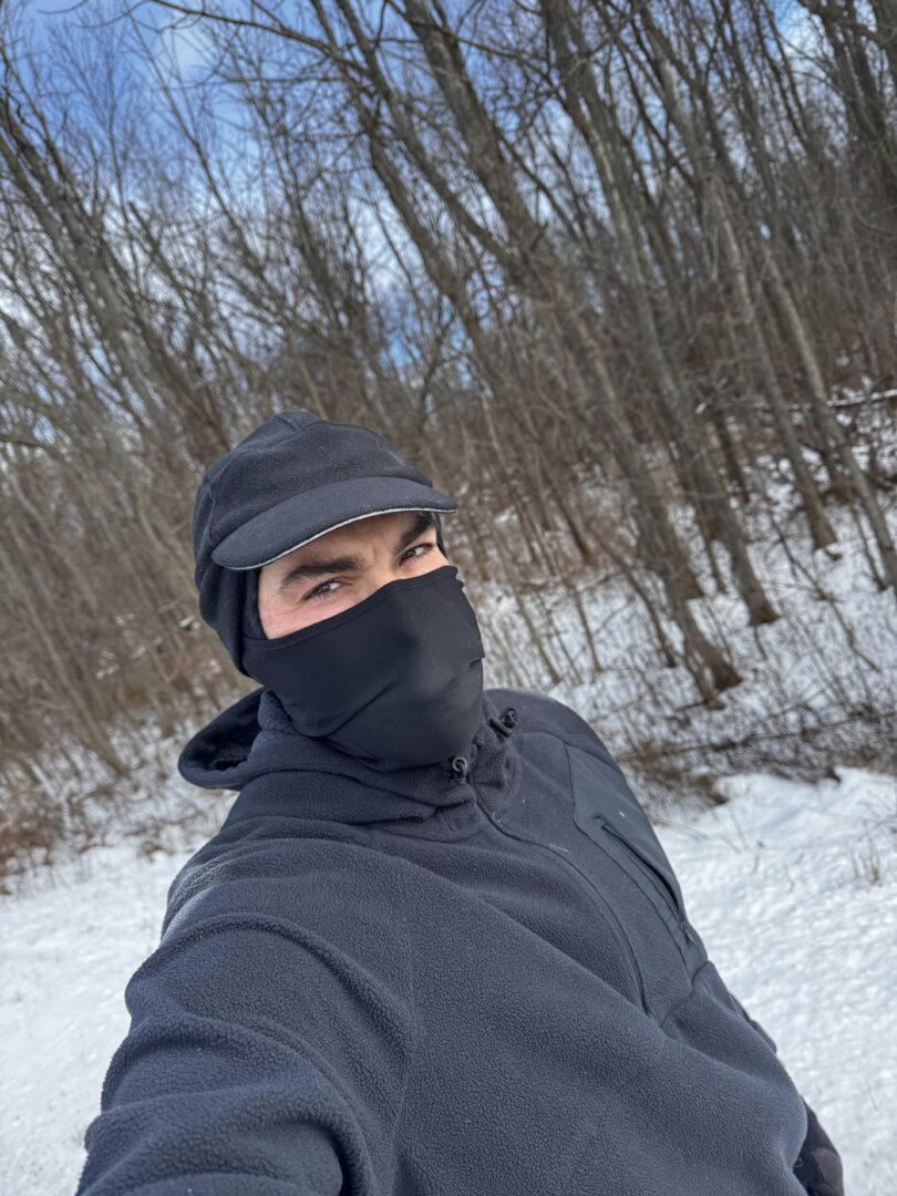 a man wearing a mask and hat in the snow