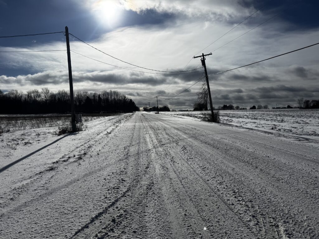 a snow covered road with power lines and trees