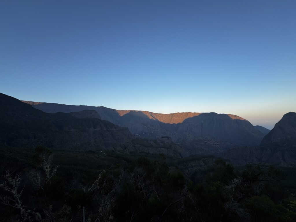 a mountain range with trees and blue sky