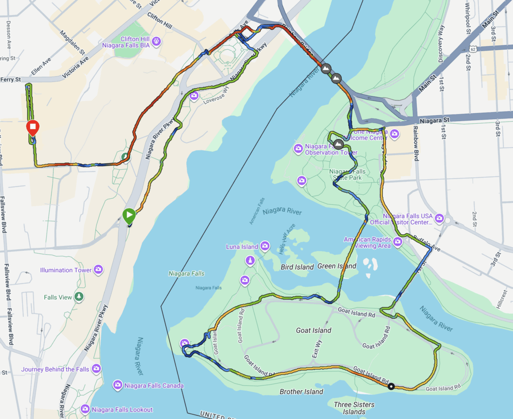 The image is a map showing a route around the Niagara Falls area. The route is marked with a multicolored line, indicating a path that starts and ends at different points. Key landmarks such as Niagara Falls, Goat Island, and the Niagara River are labeled. The map includes streets, parks, and other points of interest like the Niagara Falls State Park and the American Rapids Viewing Area. The route crosses bridges and loops around islands, highlighting a scenic path through the area.
