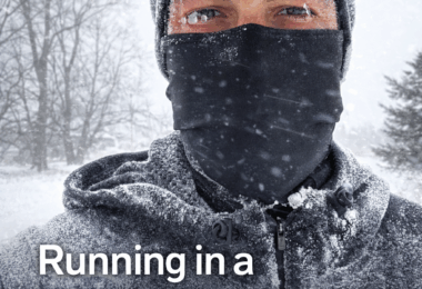 A person is outdoors in a snowy environment, wearing a hat and a face covering. Their eyebrows and eyelashes are frosted. The temperature is indicated as 8 degrees. Text on the image reads: "Running in a Winter Storm: What to Wear, How to Stay Safe, and When to Stay Inside." Snow-covered trees are visible in the background.